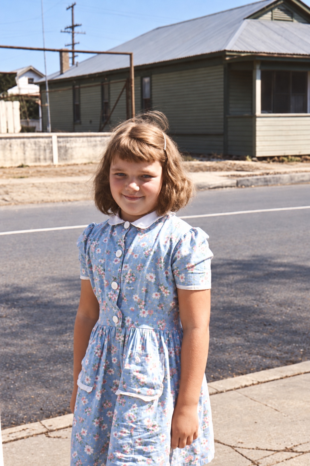 Judith as a child, smiling outdoors in a blue floral dress.