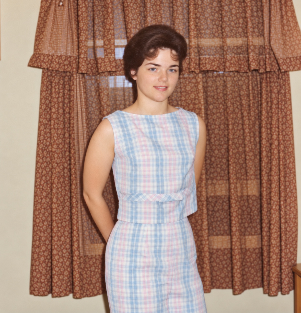 Judith standing in a sleeveless blue and pink plaid outfit.